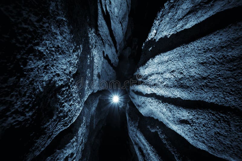 Dark blue cave with light from caver flashlight shining. Dark blue cave with light from caver flashlight shining