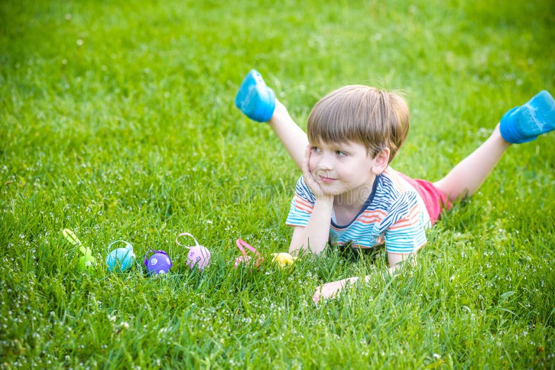 Caza del niño pequeño para el huevo de Pascua en jardín de la primavera el día de Pascua imagen de archivo libre de regalías Caza del niño pequeño para el huevo de Pascua en jardín de la primavera el día de Pascua imagen de archivo libre de regalías