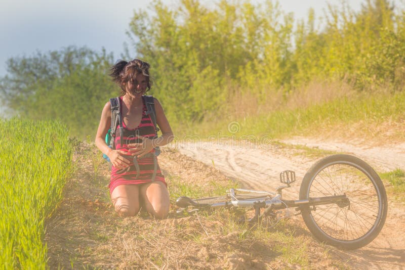 Caída bonita de la muchacha apenas de la bici de la bicicleta cerca del campo de trigo en los rayos solares La bicicleta miente e fotografía de archivo Caída bonita de la muchacha apenas de la bici de la bicicleta cerca del campo de trigo en los rayos solares La bicicleta miente e fotografía de archivo