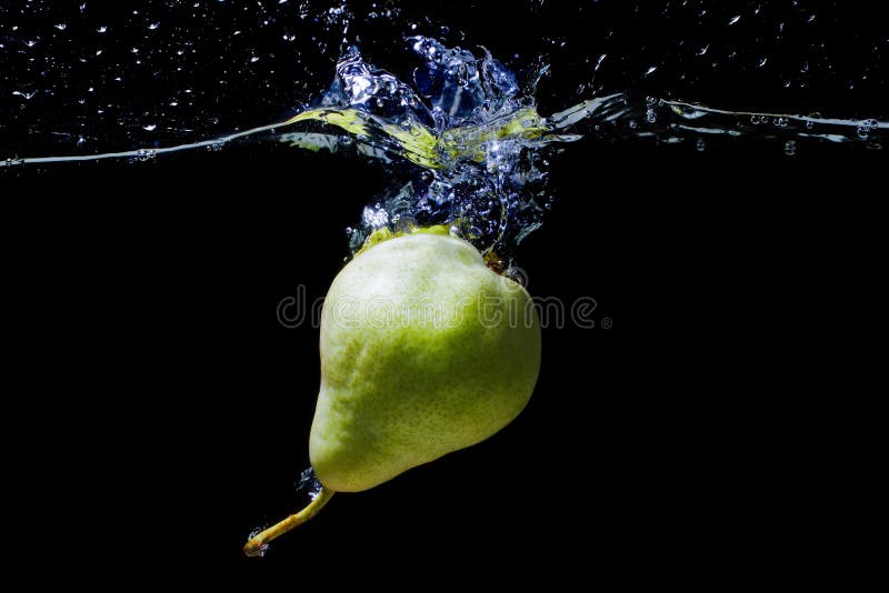 Whole green pear dropped in water with splashes isolated on black background. Whole green pear dropped in water with splashes isolated on black background