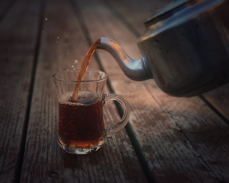 Ceai antic ceainic turnând ceai într-o ceașcă de sticlă stock photography