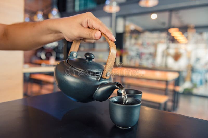 Ceainic care toarnă apă fiartă într-o ceașcă în timpul cafelei în cafenea royalty free stock photo