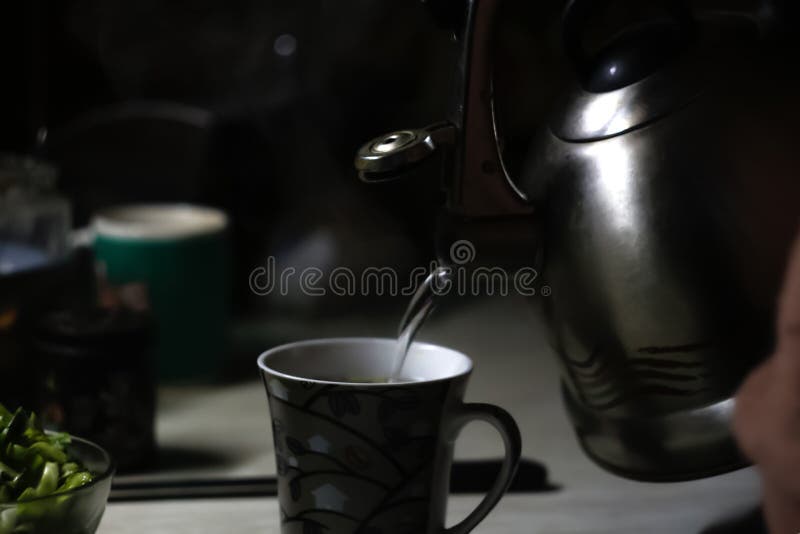 Ceainic turnat în cană. ceainicul care toarnă apă clocotită într-o ceașcă în timpul micul dejun dimineața. noapte întunecată. nu s stock images