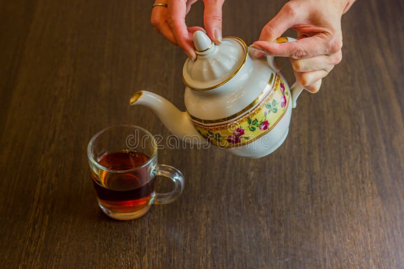Ceainicul de porțelan, de tip oldstyle, turnând ceai de la ulcior la ceașca de ceai stock images