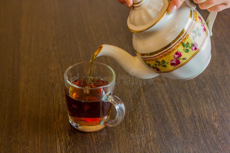 Ceainicul de porțelan, de tip oldstyle, turnând ceai de la ulcior la ceașca de ceai stock photos