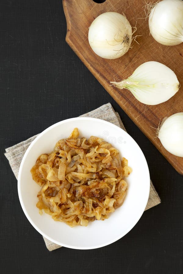 Ceapă caramelizată artizanală pe o placă albă, cu vedere de fond negru. de sus în sus. închidere stock image