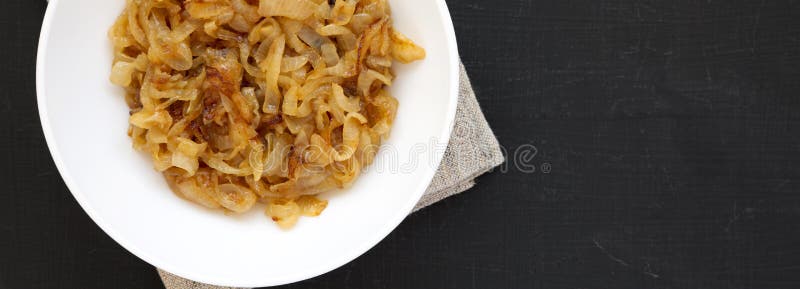 Ceapă caramelizată artizanală pe o placă albă, cu vedere la suprafață neagră. de deasupra întinderii plane de acoperire. copiere s royalty free stock image