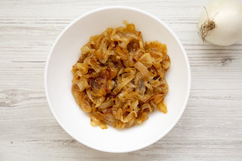 Ceapă caramelizată de calitate superioară pe o placă albă pe o suprafață albă din lemn. cheltuieli de regie fixe de deasupra. înch stock images