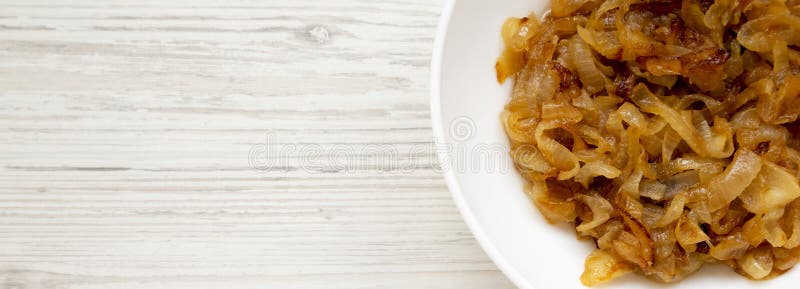 Ceapă caramelizată de casă pe o placă albă pe o suprafață albă din lemn. . royalty free stock images