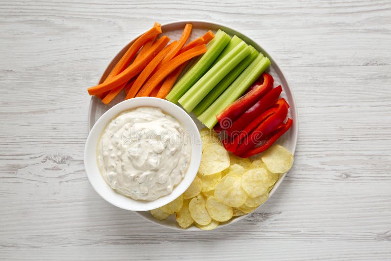 Ceapă caramelizată de uz casnic, cu chipsuri de cartofi, piper de țelină și morcov pe o suprafață albă din lemn. plat royalty free stock photo