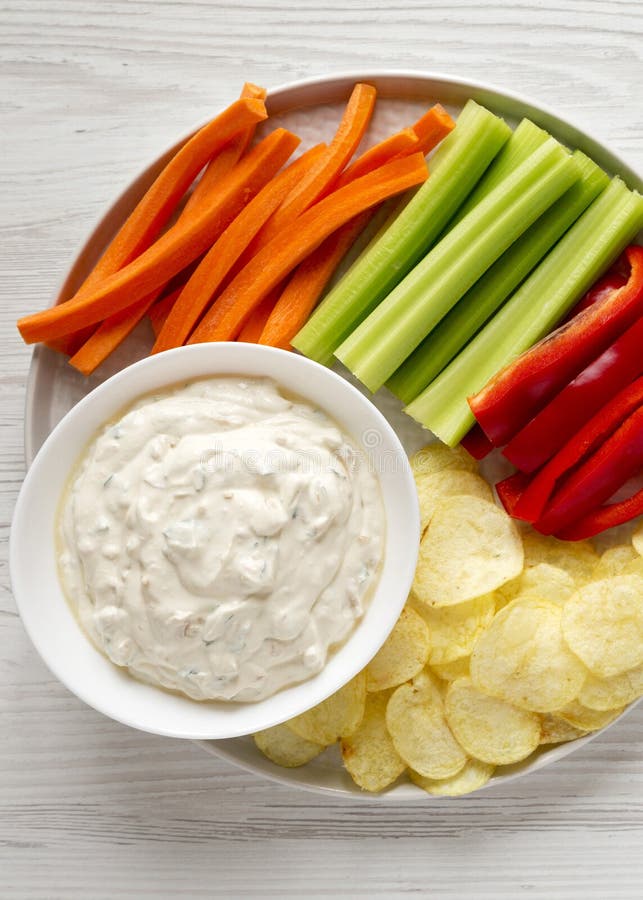 Ceapă caramelizată de uz casnic, cu chipsuri de cartofi, piper de țelină și morcov pe o suprafață albă din lemn. plat stock image