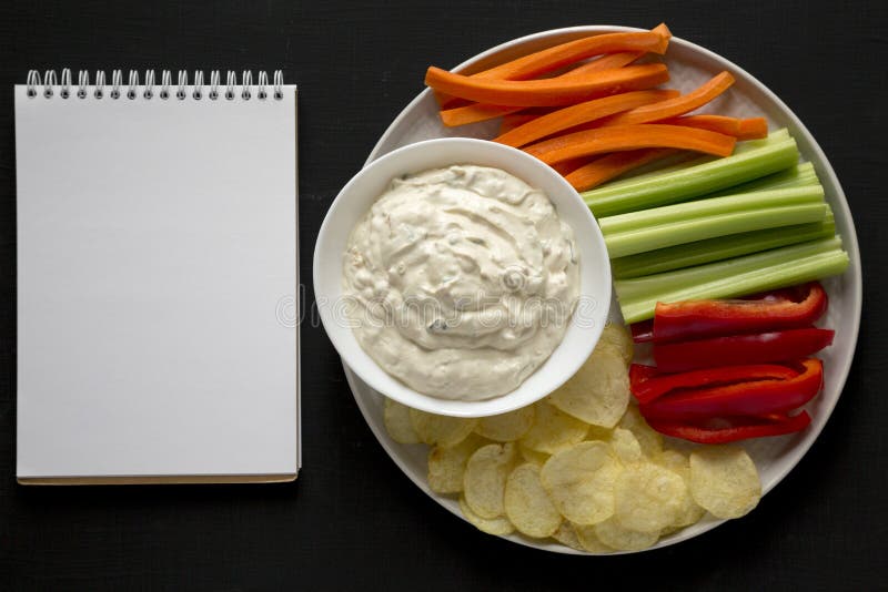 Ceapă caramelizată de uz casnic, cu chipsuri de cartofi și cu notebook-uri goale pe o vedere de fond neagră. suprafață plană royalty free stock image