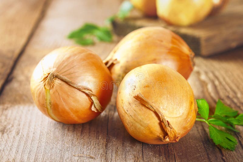 Cebola amarela com salsa num tampo de madeira foto de stock