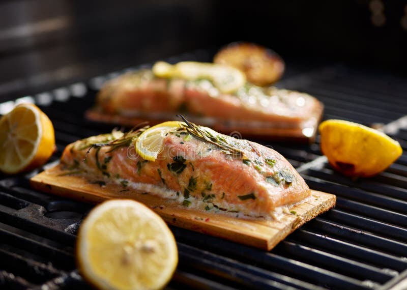 Cedar plank salmon with lemon and rosemary on grill