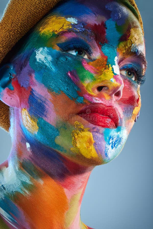 Ceea ce cred artiștii că este adesea exprimat prin culori. O fotografie în studio a unei tinere care se dă cu vopsea multicoloră p stock photos