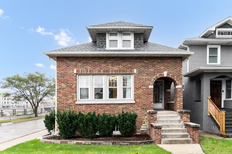 OAK PARK, IL, USA - AUGUST 3, 2020: A brick bungalow with stairs leading to arched doorway. OAK PARK, IL, USA - AUGUST 3, 2020: A brick bungalow with stairs leading to arched doorway.