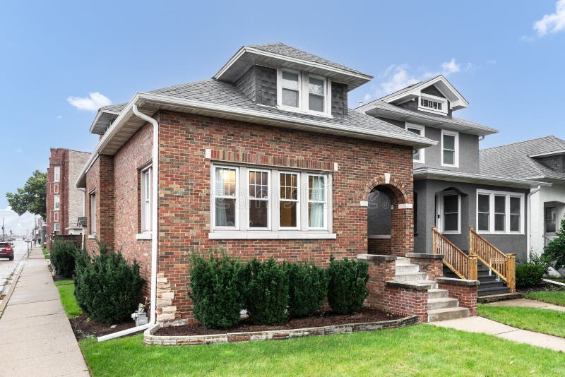 OAK PARK, IL, USA - AUGUST 3, 2020: A brick bungalow with stairs leading to arched doorway. OAK PARK, IL, USA - AUGUST 3, 2020: A brick bungalow with stairs leading to arched doorway.