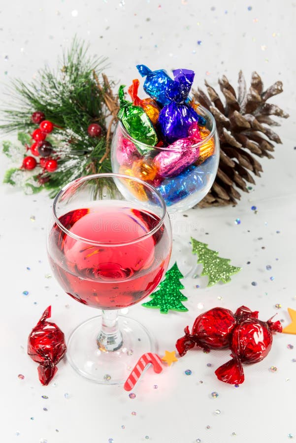 Christmas party celebrations with wine and wrapped chocolate candy sweets. Treats to enjoy the merry holiday season. On a sparkly white background. Christmas party celebrations with wine and wrapped chocolate candy sweets. Treats to enjoy the merry holiday season. On a sparkly white background.