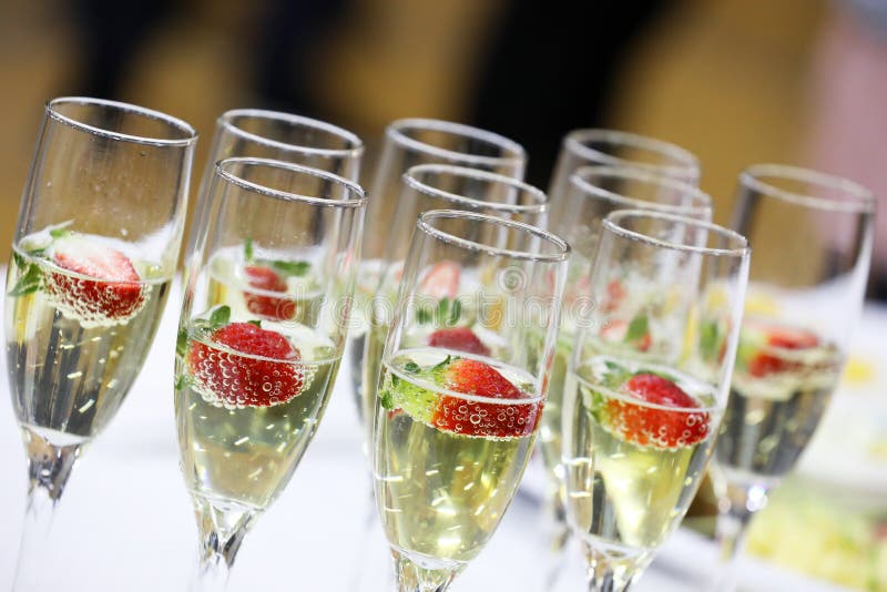 Close up of multiple clear glass champagne stem flutes with strawberries and bubbles. Fizz and bubbles on a tray. Sparkling wine glasses ready for toasting. Close up of multiple clear glass champagne stem flutes with strawberries and bubbles. Fizz and bubbles on a tray. Sparkling wine glasses ready for toasting