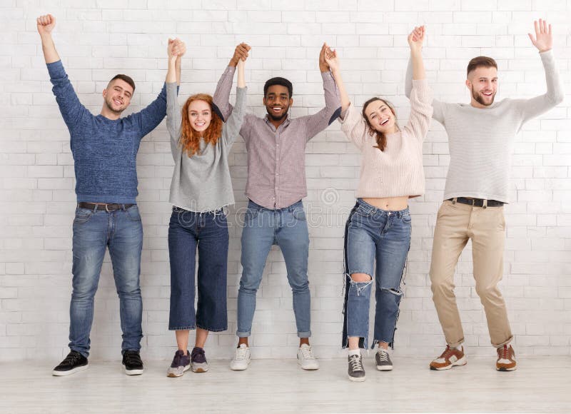 Celebrating succeess. Friends raised hands over white wall