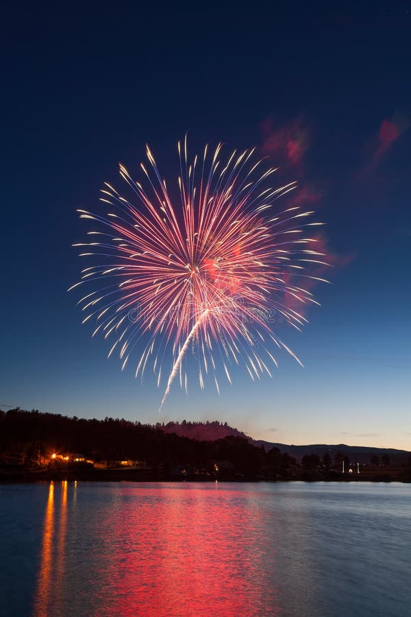 Celebration Fireworks Display Over a Mountain Lake at Dusk Stock Photo