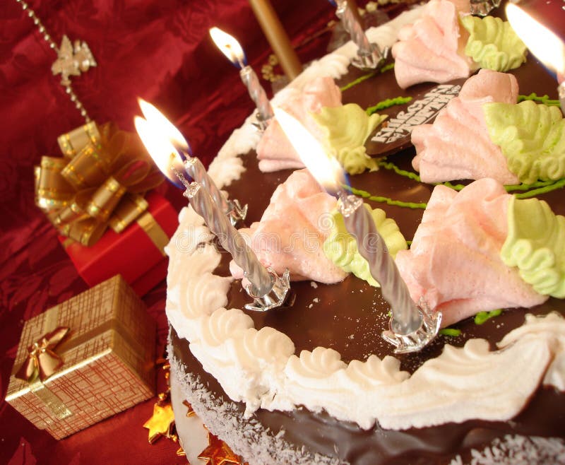 Celebratory table (birthday cake and candles, gift boxes) on red