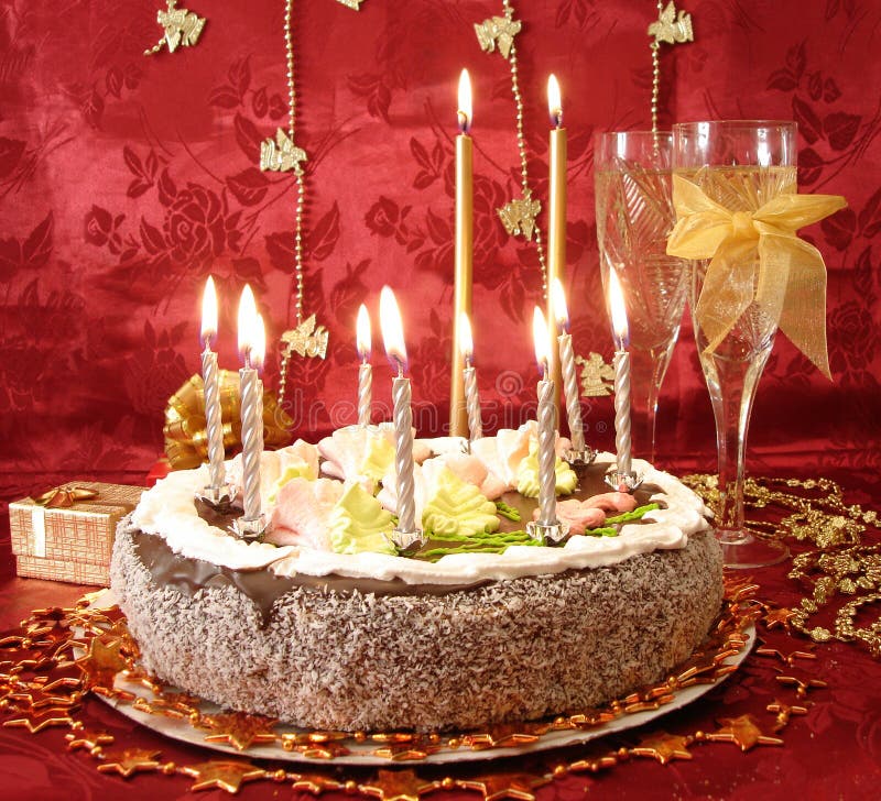 celebratory table (cake and candles, two glasses with champagne, gift boxes) on red