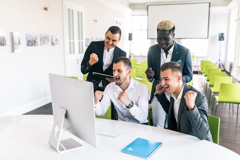 Celebrazione del successo Gruppo di gente di affari che alza le loro armi e che sembra felice mentre sedendosi intorno allo scrit immagine stock Celebrazione del successo Gruppo di gente di affari che alza le loro armi e che sembra felice mentre sedendosi intorno allo scrit immagine stock
