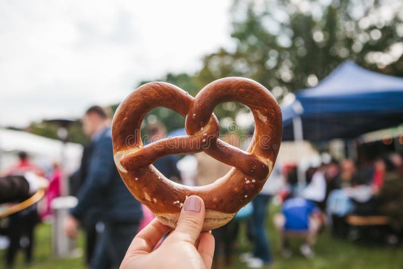 Celebração do festival alemão famoso Oktoberfest que da cerveja a pessoa realiza em sua mão um pretzel tradicional chamou foto de stock royalty free Celebração do festival alemão famoso Oktoberfest que da cerveja a pessoa realiza em sua mão um pretzel tradicional chamou foto de stock royalty free