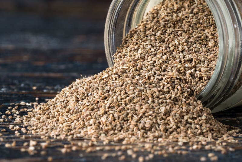 Close up view of celery seeds spilling from a spice jar.