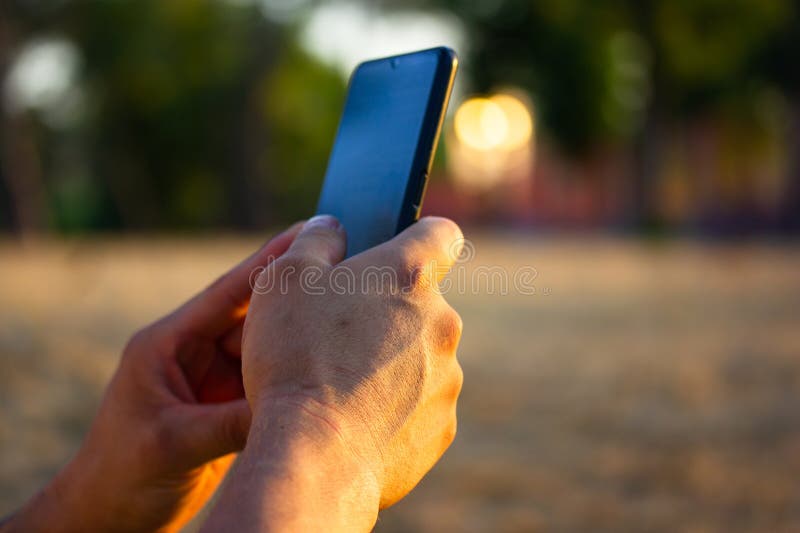 Telefon mobil în mâini de om. bărbat față-față utilizează telefon mobil smartphone în parc royalty free stock photography