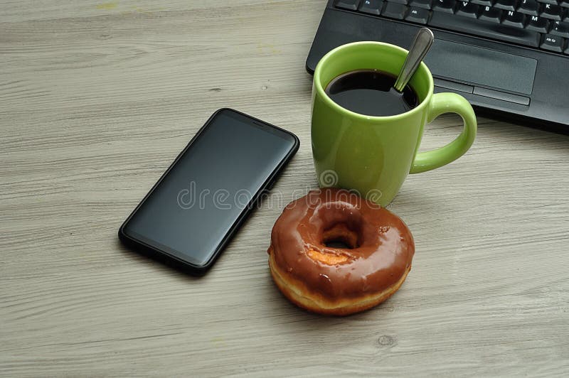 A cellphone, laptop, doughnut and cup of coffee