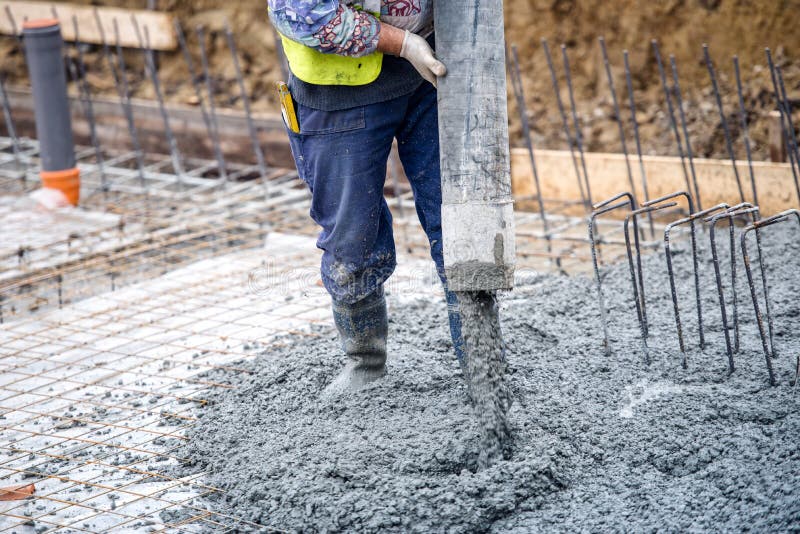 Cemento o calcestruzzo di versamento del muratore della costruzione con il tubo di pompa