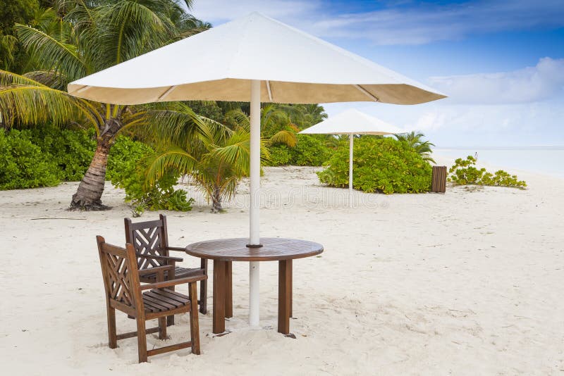 table with two chairs under a sunshade at a tropical beach. table with two chairs under a sunshade at a tropical beach