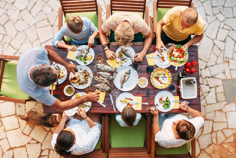 Cena grande de la familia del miltigeneration en proceso Imagen vertical de la visión superior en la tabla con la comida y las ma fotografía de archivo libre de regalías