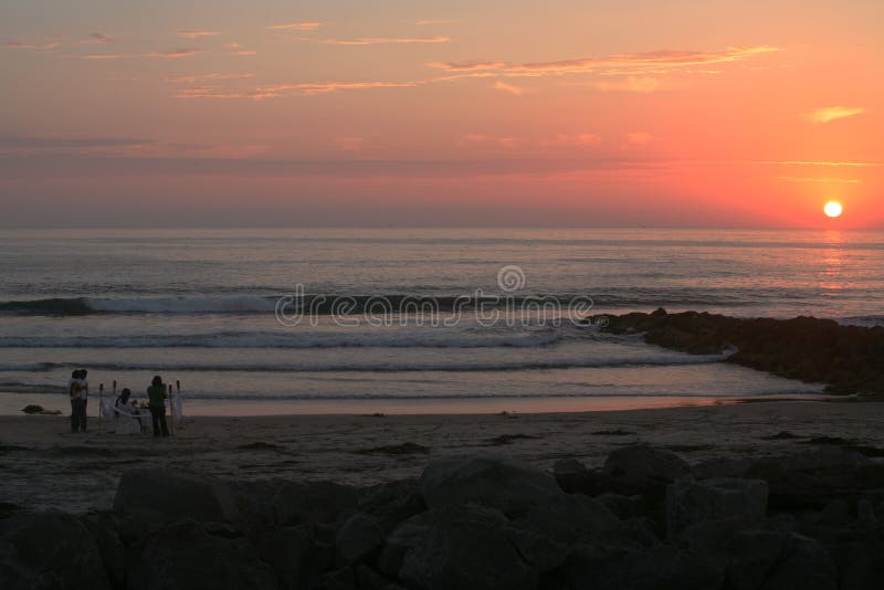 This stock photo depicts a young couple celebrating a wedding anniversary by having a romantic candle-lit dinner on the beach as the sun sets over the horizon at Imperial Beach, CA. This stock photo depicts a young couple celebrating a wedding anniversary by having a romantic candle-lit dinner on the beach as the sun sets over the horizon at Imperial Beach, CA.