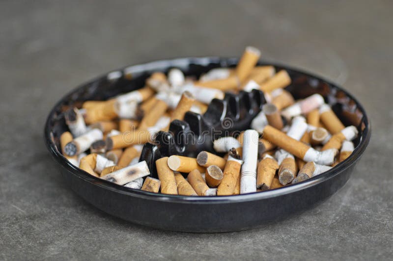 Full ashtray of cigarettes on table, close-up. Full ashtray of cigarettes on table, close-up.