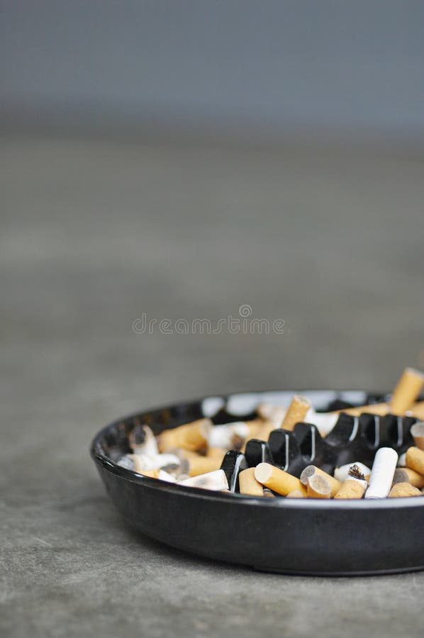 Full ashtray of cigarettes on table, close-up. Full ashtray of cigarettes on table, close-up.