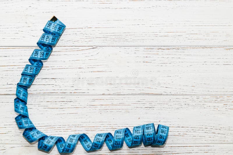 Centimeter for measuring the waist or for sewing on a wooden background, diet concept. stock photography Centimeter for measuring the waist or for sewing on a wooden background, diet concept. stock photography