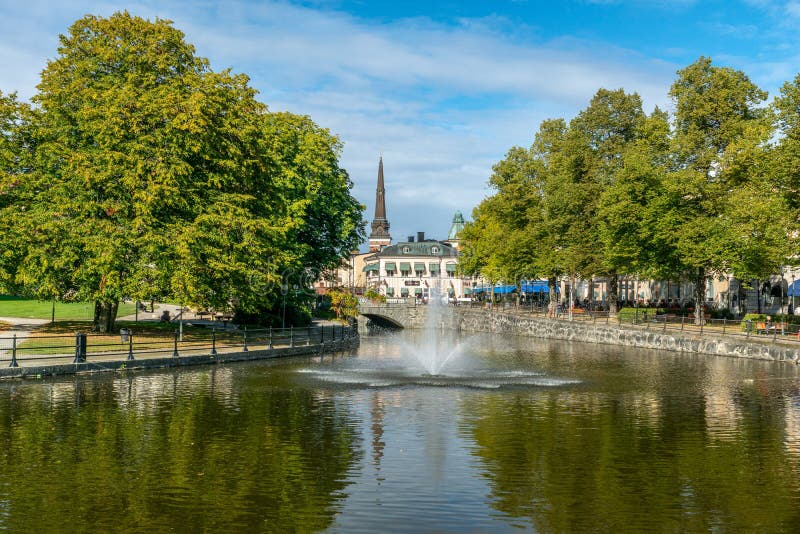 Västerås, Sweden, 21-09-2016. Summer view of the central part of Västerås in Sweden, with lush green trees and a fountain in the river passing through the city. Västerås, Sweden, 21-09-2016. Summer view of the central part of Västerås in Sweden, with lush green trees and a fountain in the river passing through the city