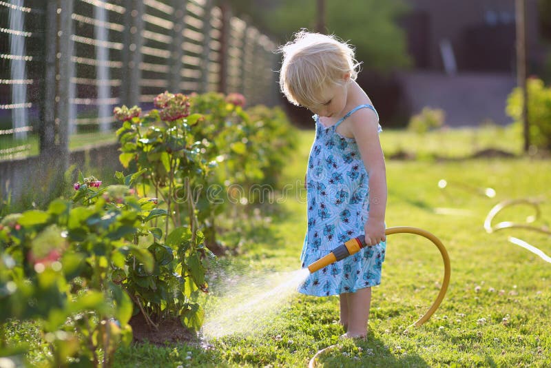 Centrales d'arrosage de petite fille dans le jardin photos stock Centrales d'arrosage de petite fille dans le jardin photos stock
