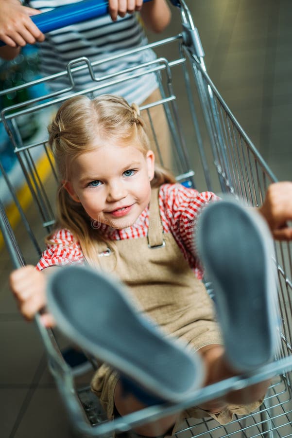 Centre sélectif de peu de fille s'asseyant dans le caddie photo stock