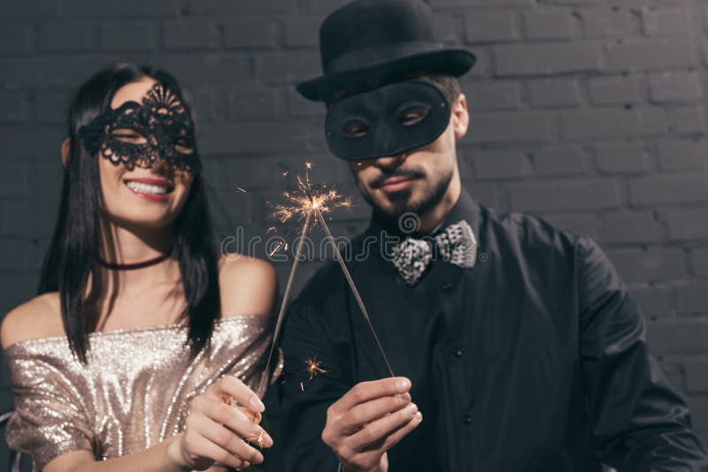centre sélectif des couples multi-ethniques élégants dans des masques de Noël avec des étincelles à nouveau images stock centre sélectif des couples multi-ethniques élégants dans des masques de Noël avec des étincelles à nouveau images stock