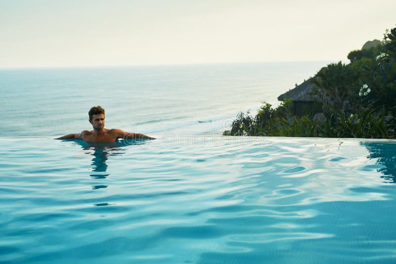 Centro turístico de lujo Hombre que se relaja en piscina de la nadada Vacaciones del viaje del verano fotos de archivo libres de regalías Centro turístico de lujo Hombre que se relaja en piscina de la nadada Vacaciones del viaje del verano fotos de archivo libres de regalías