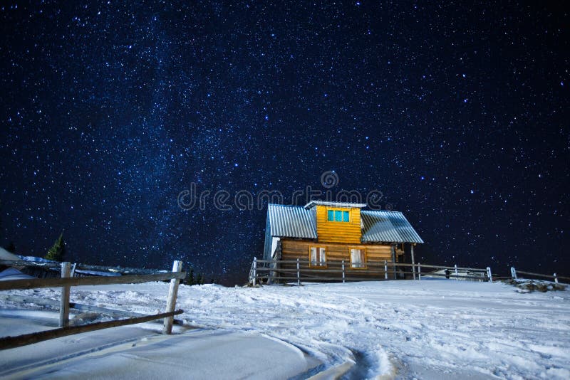 Cenário bonito de uma casa de madeira do céu estrelado do inverno da noite, de uma foto longa da exposição de estrelas da meia-no imagens de stock Cenário bonito de uma casa de madeira do céu estrelado do inverno da noite, de uma foto longa da exposição de estrelas da meia-no imagens de stock