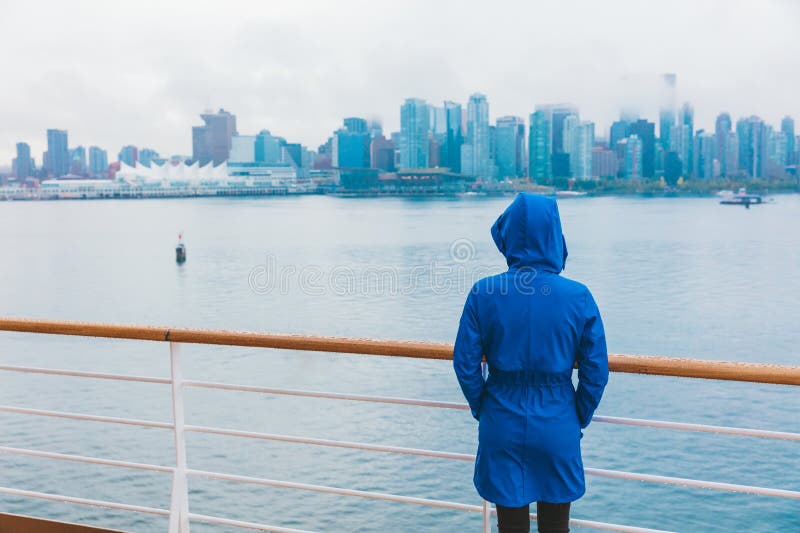 Cenário da cidade do outono, mulher caminhando sozinha sob a chuva vestindo capa de chuva azul no dia frio molhado. linha do horiz