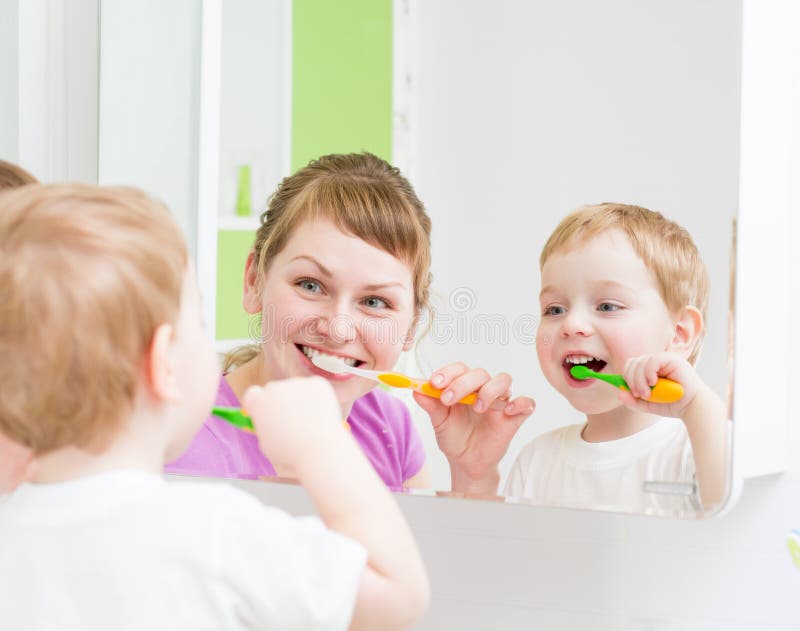 Cepillado de dientes feliz de la madre y del niño en cuarto de baño imagenes de archivo Cepillado de dientes feliz de la madre y del niño en cuarto de baño imagenes de archivo