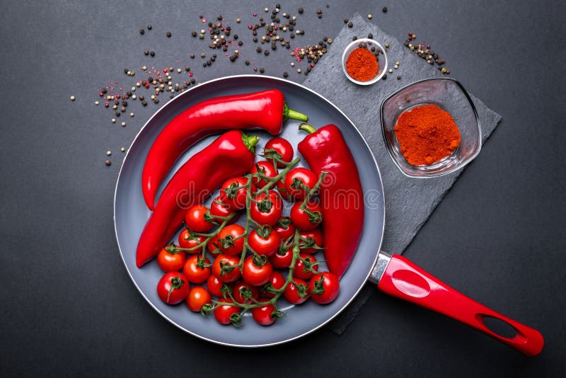 Ceramic pan full of fresh vegetables in red color: tomatoes and peppers.