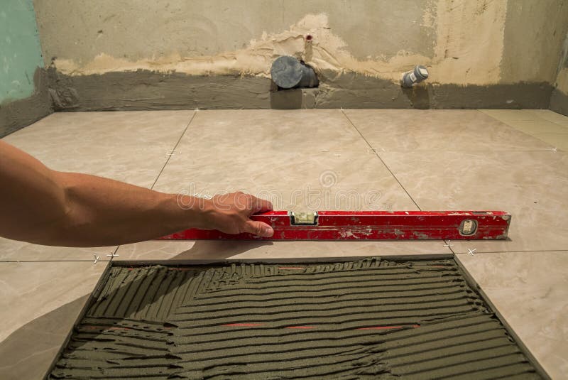 Ceramic Tiles and Tools for Tiler. Worker Hand Installing Floor Tiles