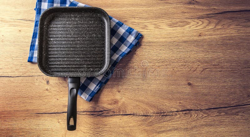 Ceramische grillpan op keuken houten lijst met blauw geruit tafelkleed royalty-vrije stock afbeelding Ceramische grillpan op keuken houten lijst met blauw geruit tafelkleed royalty-vrije stock afbeelding